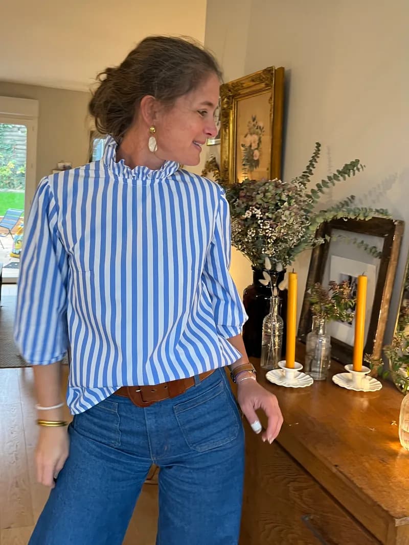 Femme souriante portant une blouse rayée bleue et blanche à col cheminée froufrou, ceinture cuir — vêtements femme fait main By Mésange