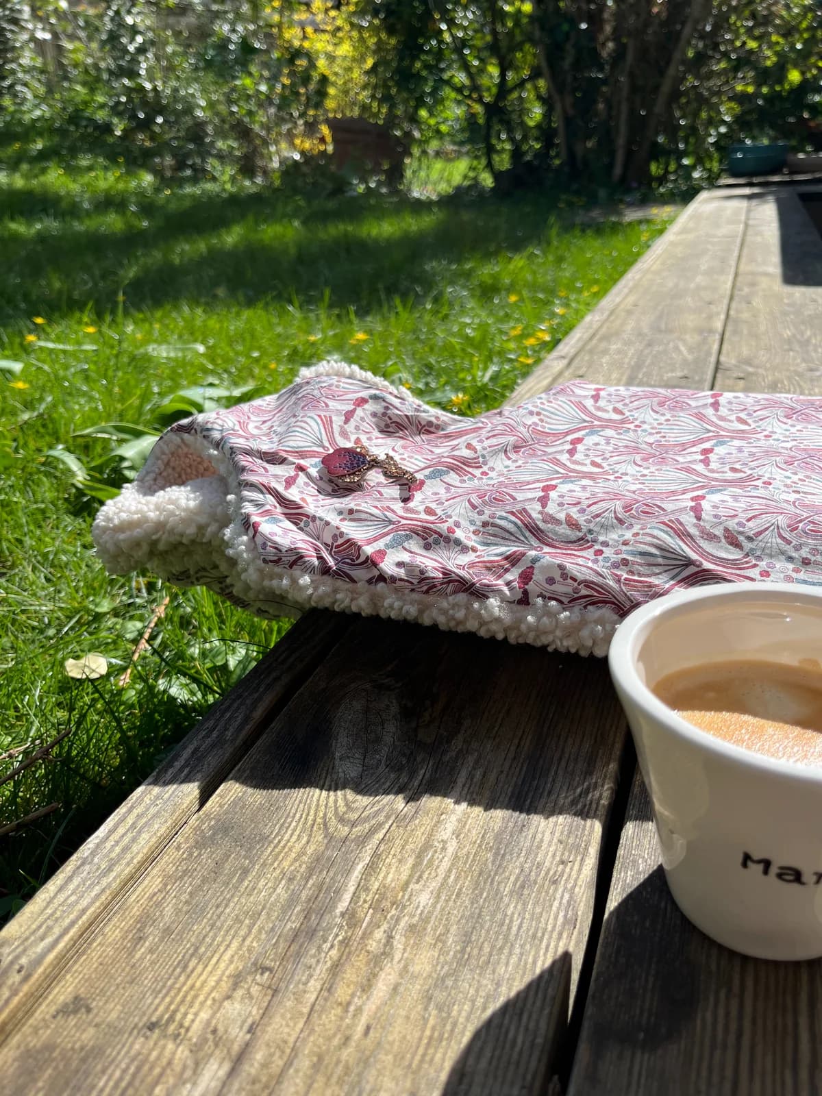 Col liberty rose pompons Col en tissu liberty rose à pompons posé sur une table de jardin avec café — By Mésange