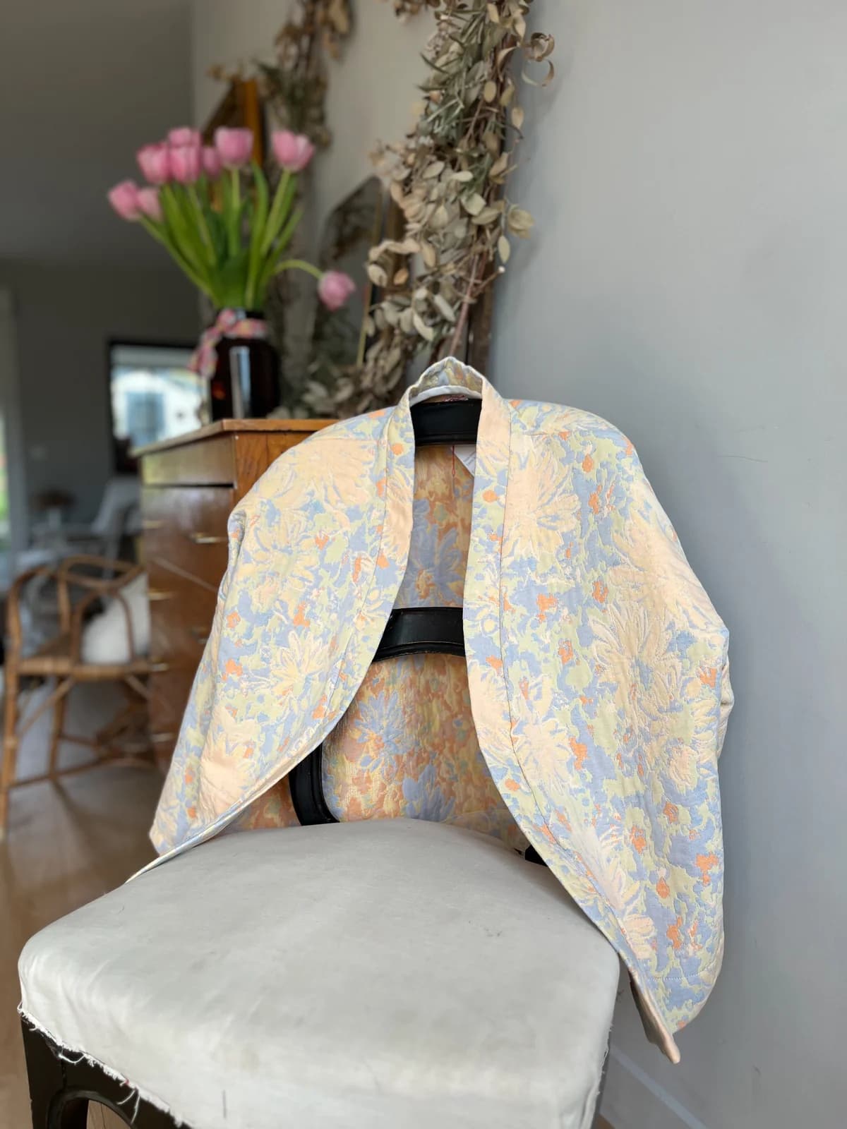 Détail veste jacquard Veste jacquard fleurie pastel By Mésange posée sur une chaise — détail tissu
